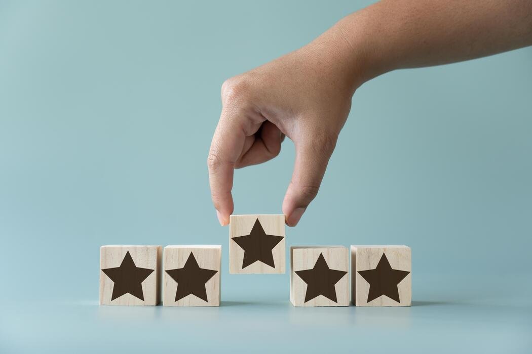 A hand arranging five wooden star blocks